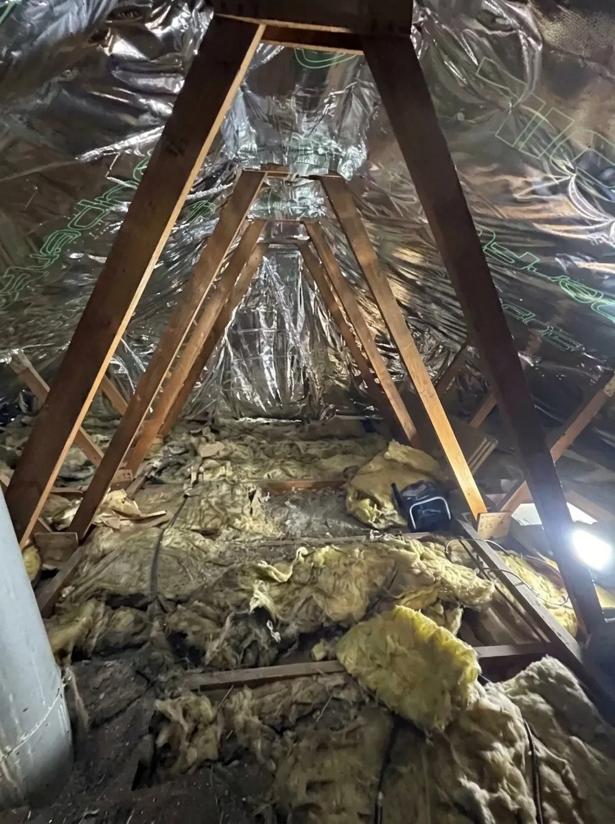 Loft inspection in a Kirklees roof space showing rafters, foil membrane and mineral wool insulation